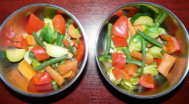 Fresh vegetables recommended for African Greys — leafy greens, carrot, broccoli, and bell pepper, the fresh half of Roys's daily diet